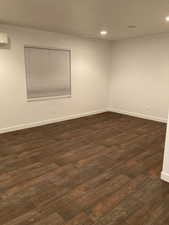 Empty room with baseboards, recessed lighting, dark wood-style floors, and a wall unit AC