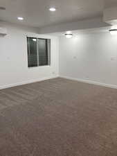 Unfurnished room with dark carpet, a wall mounted air conditioner, recessed lighting, and baseboards