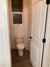 Bathroom featuring baseboards, toilet, and wood finished floors
