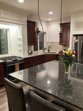 Kitchen featuring dark brown cabinets, decorative backsplash, stainless steel appliances, and a sink