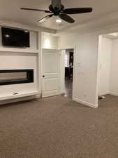 Master bedroom with a glass covered fireplace, ceiling fan, baseboards, and carpet flooring