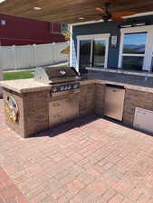 View of patio with grilling area, fence, an outdoor kitchen, and a ceiling fan