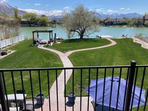 View of community featuring a water and mountain view, a pergola, fence, and a lawn