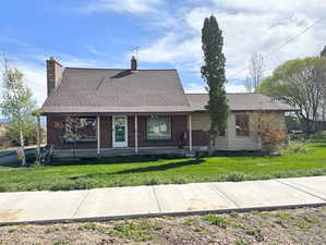 View of front of property featuring brick siding, roof with shingles, and a front yard