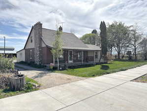 View of front of property with a chimney, driveway, a porch, brick siding, and a front yard
