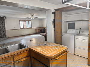 Kitchen featuring a sink, open floor plan, separate washer and dryer, ceiling fan, and butcher block counters
