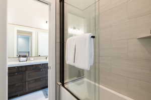 Full bathroom with enclosed tub / shower combo and vanity