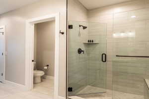 Full bathroom featuring tile patterned floors, baseboards, a shower stall, and toilet