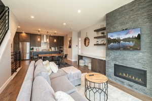 Living room featuring baseboards, wood finished floors, a fireplace, and recessed lighting