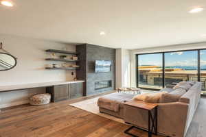 Living room with a fireplace, wood finished floors, and recessed lighting