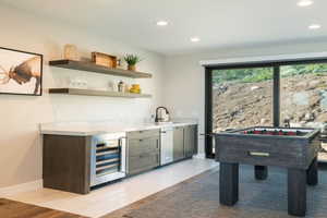 Bar featuring stainless steel dishwasher, beverage cooler, wet bar, baseboards, and recessed lighting