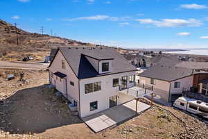 Rear view of property with a shingled roof, a patio area, and stucco siding