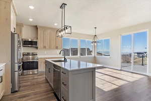 Kitchen with a textured ceiling, recessed lighting, appliances with stainless steel finishes, dark wood-type flooring, and a sink