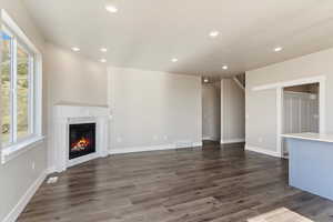 Unfurnished living room with a tiled fireplace, dark wood-style flooring, baseboards, and recessed lighting