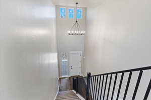 Stairway featuring a towering ceiling, a chandelier, and wood finished floors