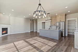 Kitchen featuring light countertops, wood finished floors, open floor plan, stainless steel refrigerator with ice dispenser, and an inviting chandelier