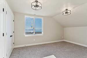 Bonus room featuring carpet flooring, an inviting chandelier, vaulted ceiling, and visible vents