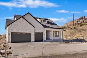 View of front of house with driveway, a garage, brick siding, and roof with shingles