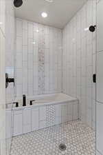 Bathroom with tile walls, tile patterned flooring, and tiled shower
