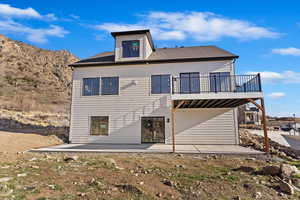 Rear view of property featuring a deck with mountain view and a patio area