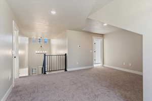 Additional living space with a notable chandelier, carpet flooring, a textured ceiling, baseboards, and visible vents