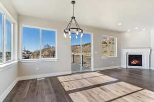 Unfurnished dining area featuring a tile fireplace, wood finished floors, baseboards, recessed lighting, and an inviting chandelier