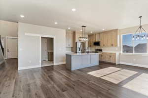 Kitchen with light brown cabinetry, light countertops, a notable chandelier, and appliances with stainless steel finishes