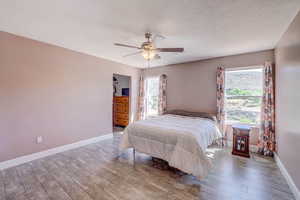 Bedroom featuring baseboards, a ceiling fan, and wood finished floors