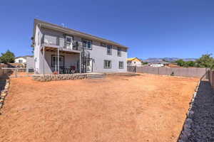 Rear view of property featuring a deck with mountain view, a fenced backyard, stairs, and stucco siding