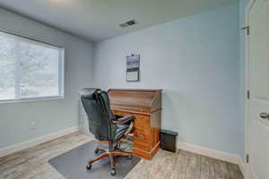 Home office with wood finished floors, visible vents, and baseboards