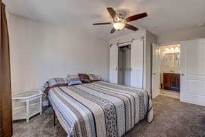 Bedroom featuring baseboards, carpet floors, ceiling fan, and a barn door