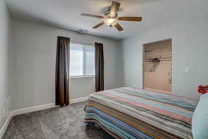 Carpeted bedroom featuring a textured ceiling, visible vents, a ceiling fan, and baseboards