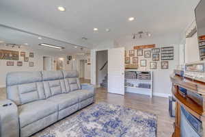 Living room with wood finished floors, baseboards, recessed lighting, and stairs