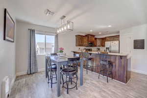 Dining area with baseboards, visible vents, and light wood-style flooring