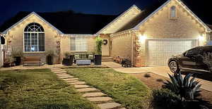 View of front facade featuring entry steps, brick siding, a yard, and a garage