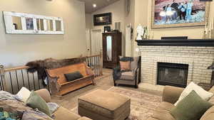 Living room featuring high vaulted ceiling, carpet flooring, a brick fireplace, visible vents, and recessed lighting