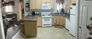 Kitchen featuring dark countertops, cream cabinetry, a sink, and white appliances