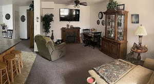 Carpeted living room featuring a fireplace and ceiling fan