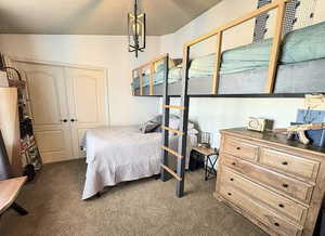 Bedroom with dark colored carpet, a closet, and an inviting chandelier
