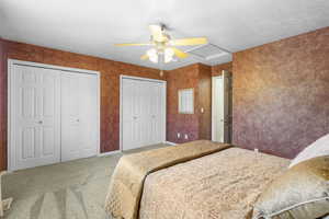 Carpeted bedroom with multiple closets and a ceiling fan