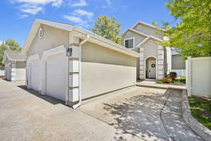 View of front facade with fence, an outdoor structure, and stucco siding