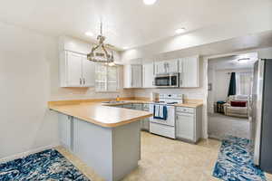 Kitchen featuring stainless steel appliances, light countertops, baseboards, a peninsula, and a textured ceiling