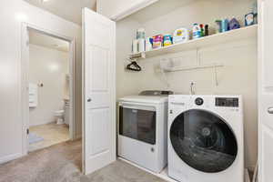 Laundry area featuring washing machine and dryer, baseboards, light carpet, and laundry area