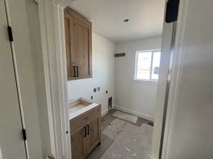 Washroom with baseboards, hookup for an electric dryer, and cabinet space