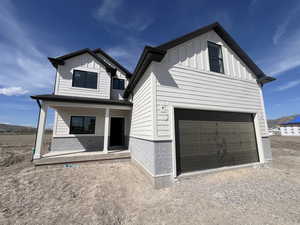 View of front of house featuring an attached garage, a porch, and board and batten siding