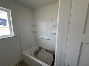 Bathroom with a washtub, baseboards, and walk in shower