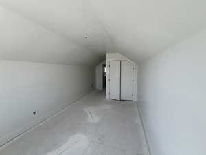 Additional living space with lofted ceiling and baseboards