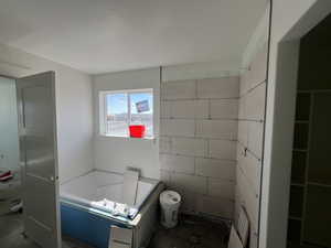 Bathroom featuring a garden tub and toilet