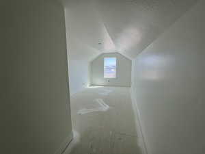 Bonus room with lofted ceiling, a textured ceiling, and baseboards