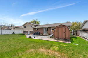 Rear view of property featuring a fenced backyard, a storage shed, a yard, and a patio